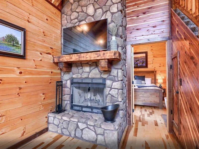 Interior of wood cabin in Hocking Hills with stone fireplace and TV.