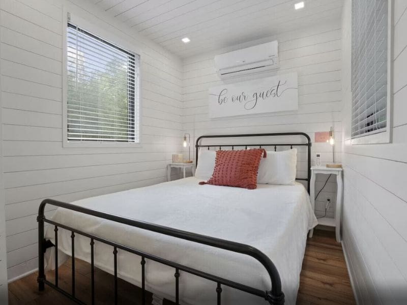 A modern bedroom in a shipping container house in Hocking Hills with a bed and an air conditioner.