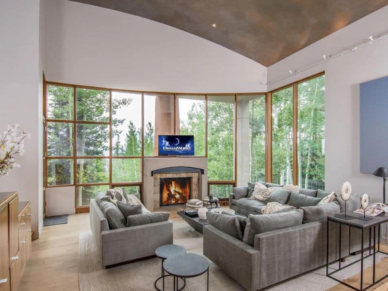 A living room with a fireplace and large windows at a ski in ski out luxury home in Aspen CO.