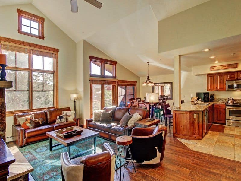 A large living room with hardwood floors, leather couches, and large windows in a Breckenridge vrbo rental.