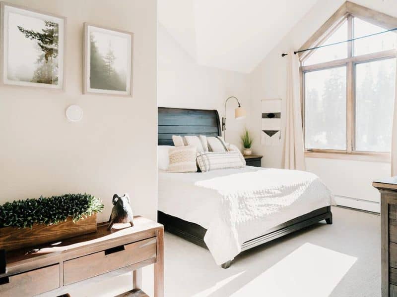 A modern white bedroom with black accents and lots of natural light at a vacation rental in Breckenridge, CO.