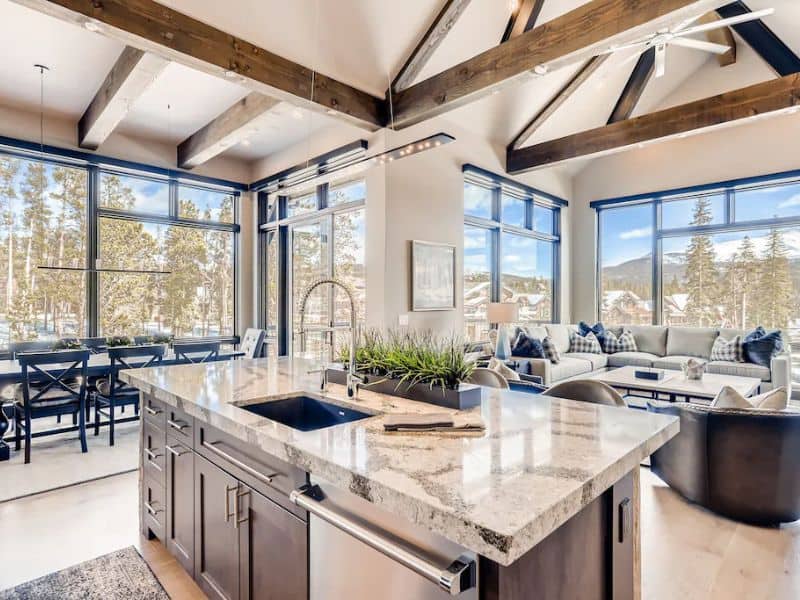 An open-plan kitchen with a grand island and panoramic mountain views at a luxury ski in ski out rental in Breckenridge.