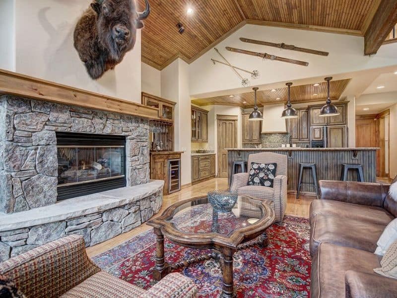 A living room with a stone fireplace and a wall-mounted cow head at a vacation rental in Breckenridge.