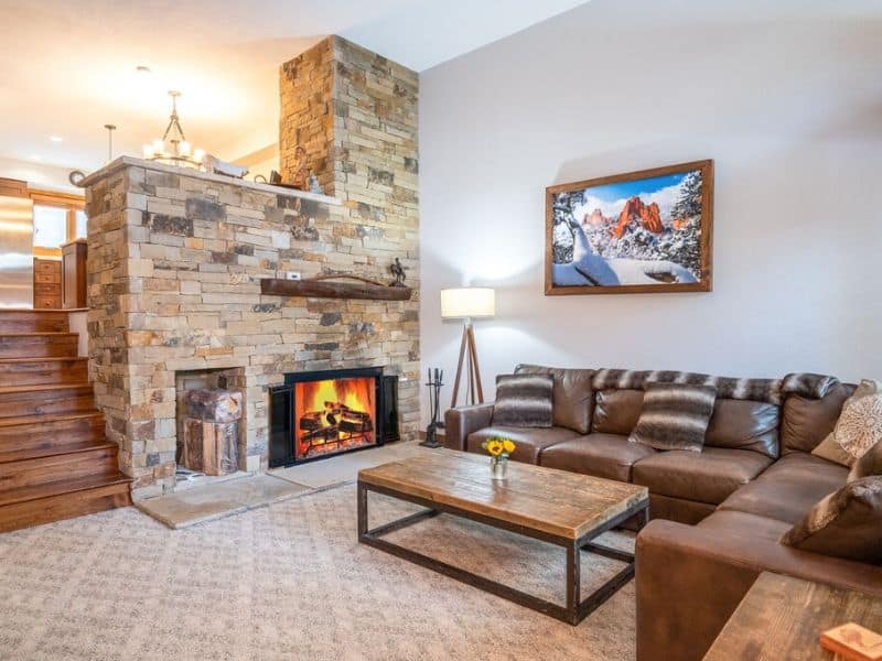 A living room with a stone fireplace and leather couches in a Breckenridge vrbo rental.