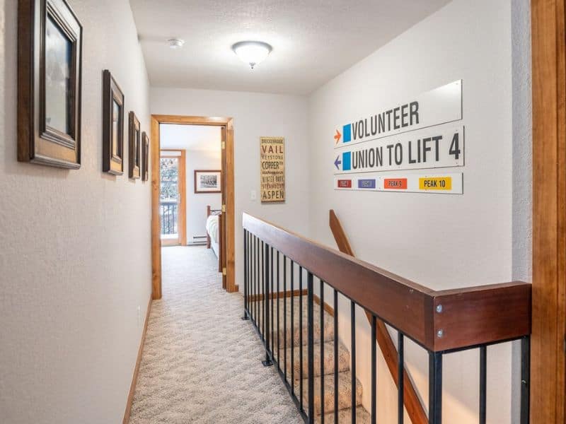 A hallway leading to rooms in a townhome in Breckenridge with ski signage on the walls.