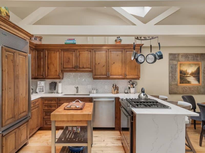 A kitchen with wood cabinets and a stainless steel stove at a ski in ski otu apartment in Aspen CO.