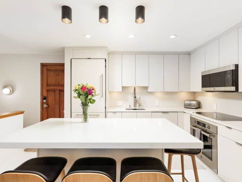 A white kitchen with black stools and a white island at a vrbo condo rental in Aspen, CO