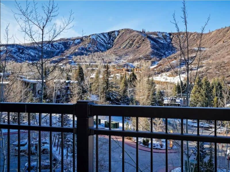 A snowy mountain view from a balcony in a ski in ski out condo in Aspen, CO.