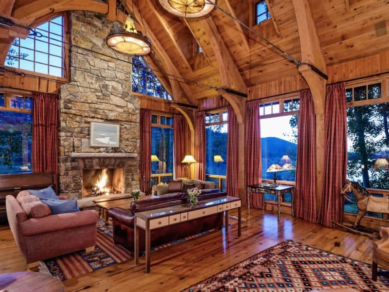 A large living room with a fireplace and large windows at a private ski-in ski-out estate near Aspen CO.