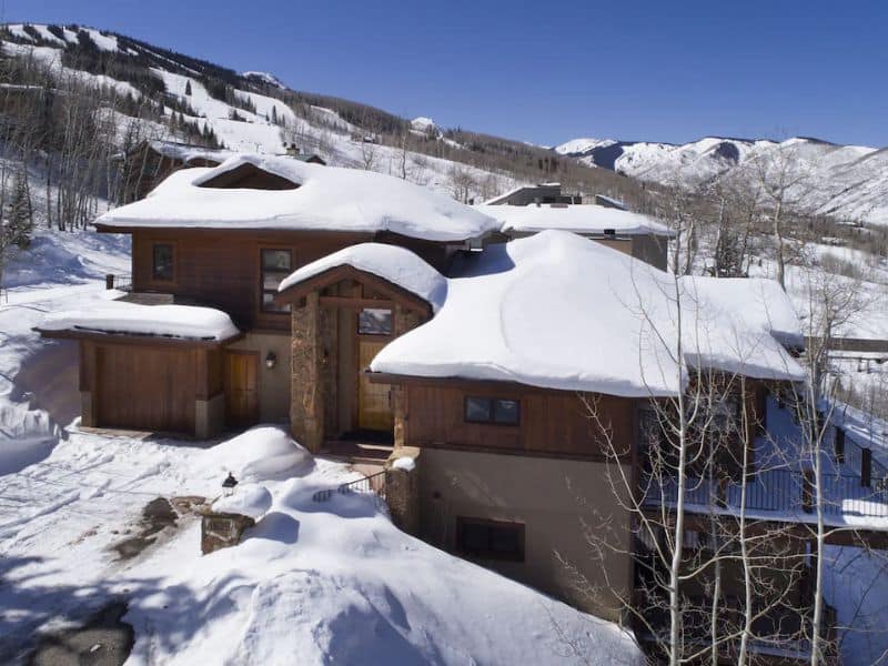 Exterior of modern Aspen CO home with snow on the roof and snow on the ground. Ski In Ski Out Aspen CO vacation rental.