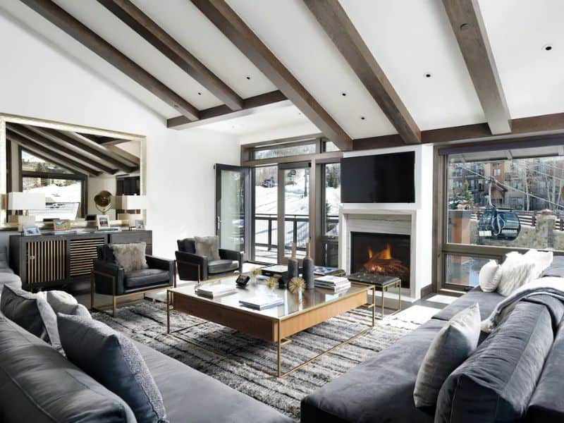A modern living room with vaulted ceilings and a fireplace in a ski-in ski-out Vrbo penthouse in Snowmass CO with gondola views.