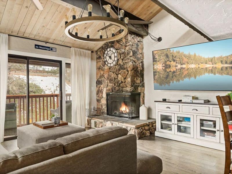 Living room with a stone fireplace and mountain views, inside one of the best cabin rentals near Snow Summit.