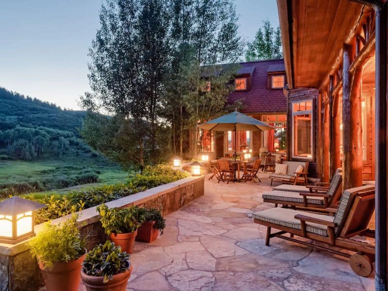 A patio overlooking a valley at a private Wildcat Ranch estate near Aspen CO with a large stone patio and outdoor furniture.