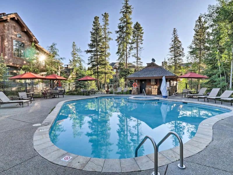 A pool surrounded by lounge chairs and trees in Breckenridge, CO.