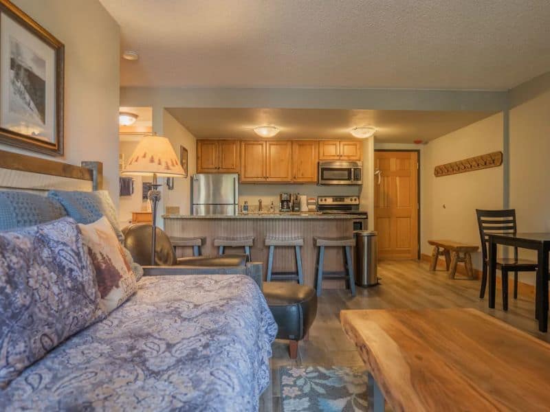 A living room with a daybed and kitchen area in a Breckenridge condo rental.