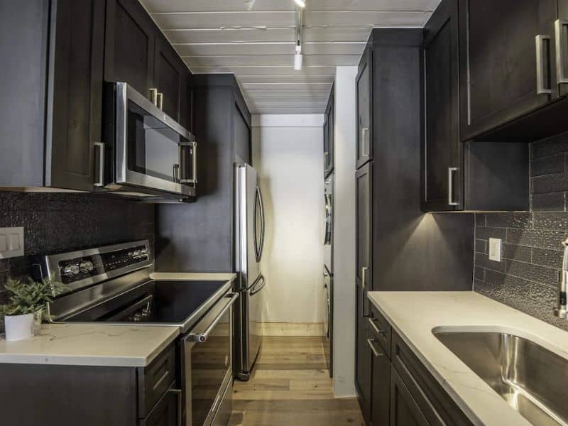 A modern kitchen with black cabinets and stainless steel appliances.