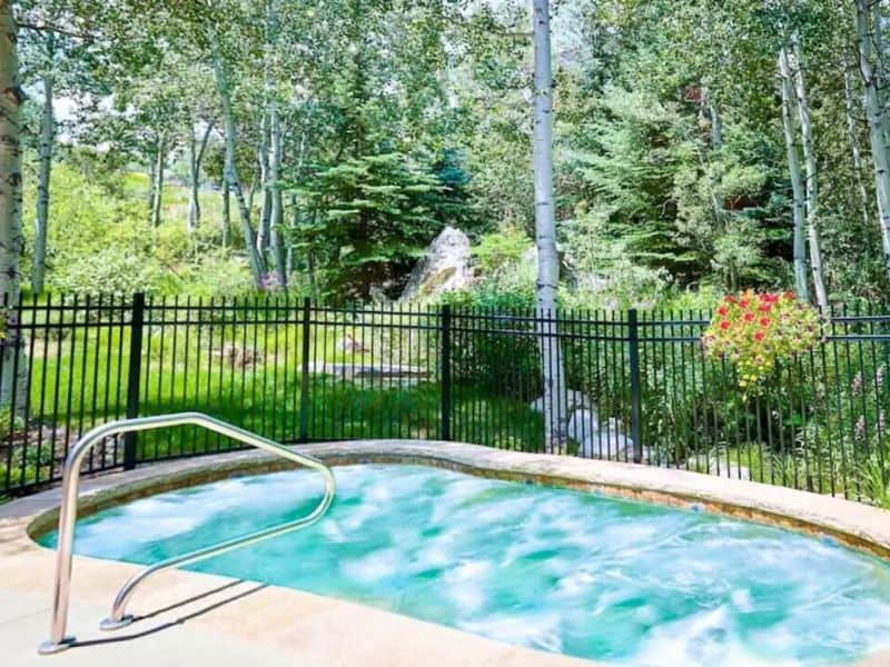 A community hot tub surrounded by trees in a wooded area.