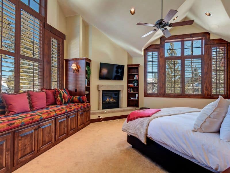 A spacious bedroom with large windows, a sitting nook, and a fireplace at a Breckenridge vrbo rental.