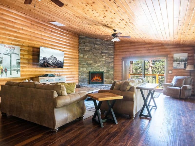 A cozy living room in a log cabin with wood floors and a fireplace located in Big Bear CA.