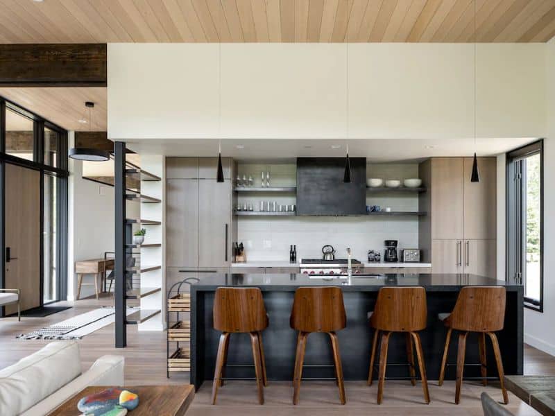 Sleek and stylish kitchen with floating shelves, bar seating, and state-of-the-art appliances in a Big Sky vacation rental, blending functionality with modern aesthetics.