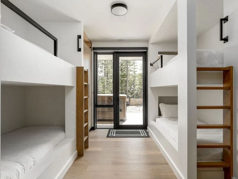 Minimalistic bunk room with clean lines and direct outdoor access, providing cozy sleeping arrangements for kids in a large Big Sky Montana vrbo rental.