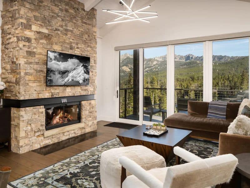 Big Sky MT ski in ski out rental with a modern living room featuring a stone fireplace and mountain views.