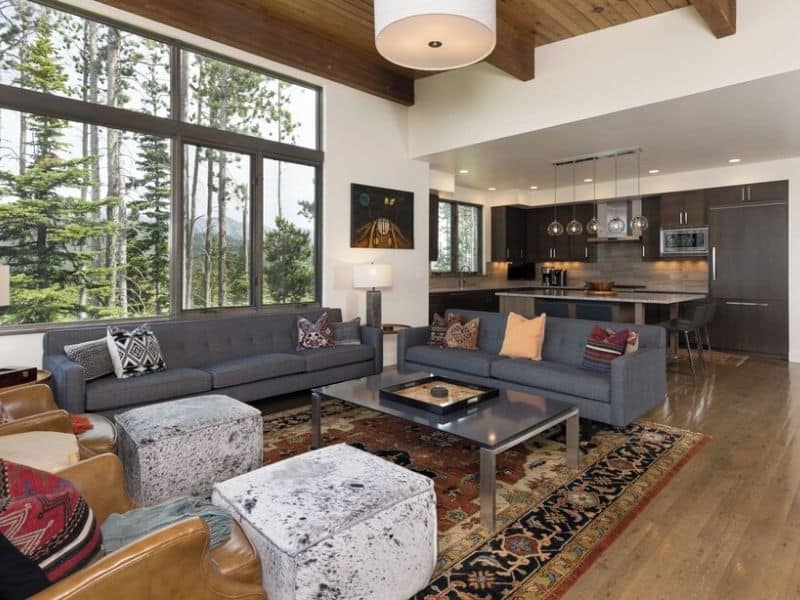Spacious living area with large windows offering forest views in a ski in ski out Big Sky MT vrbo rental.