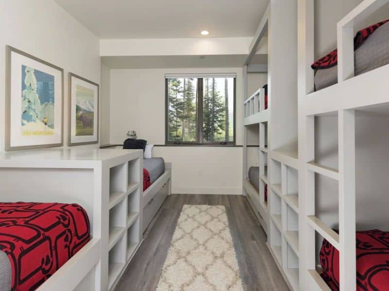 Airy bunk room with multiple beds and modern design, offering efficient sleeping arrangements in a Big Sky vacation rental, suitable for groups or families.