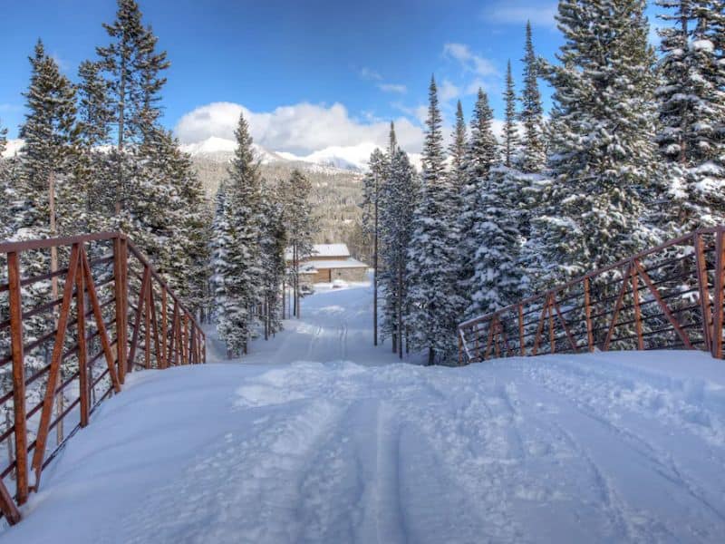Snowy path leading through a serene forested area, directly accessible from a ski in ski out Big Sky Montana rental, highlighting the prime location for ski enthusiasts.