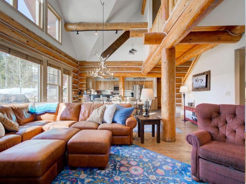Interior of a cabin featuring a large sectional sofa and open kitchen. Big Sky Montana cabin rental.