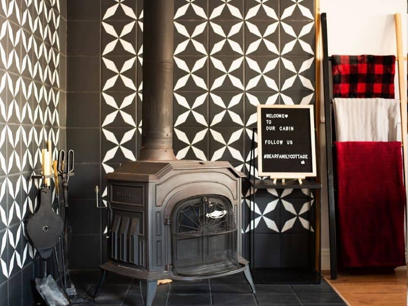 Vintage wood-burning stove against a geometric tile backdrop.