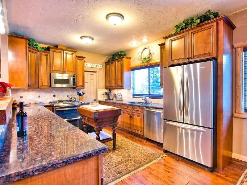 Modern and spacious kitchen in a cabin rental near Bear Mountain in Big Bear, with stainless steel appliances, granite countertops, and wooden cabinets.
