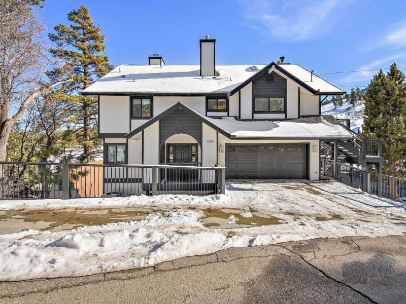 Classic black and white exterior of a Big Bear cabin with a snow-covered driveway close to the slopes.