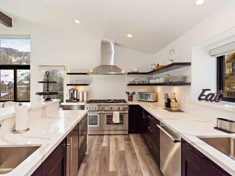 Sleek and modern kitchen with stainless steel appliances, open shelving, and white countertops in a cabin rental near Bear Mountain in Big Bear.