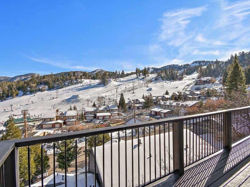 Breathtaking view from a balcony of a Big Bear winter cabin rental, showcasing the snow-covered slopes of Bear Mountain and the surrounding alpine neighborhood.