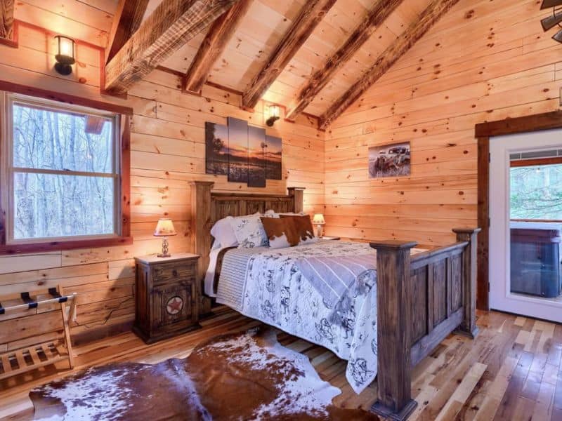 Queen bed with cow skin rug on the floor in a studio cabin rental in Hocking Hills perfect for couples