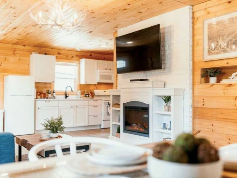 A warm, inviting kitchen with white cabinets and a central fireplace in a Hocking Hills vrbo rental, blending rustic charm with modern comforts.