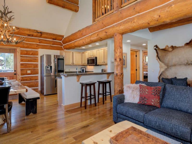 Open kitchen and dining area with bar stools and rustic decor inside a ski in ski out Big Sky Vrbo rental.