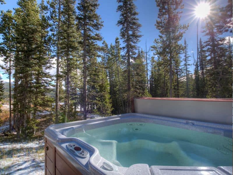 Outdoor hot tub nestled among tall pines in a Big Sky, Montana cabin rental.