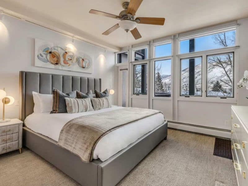 A bedroom with a king bed and large windows overlooking Aspen Mountain at a ski in ski out condo.