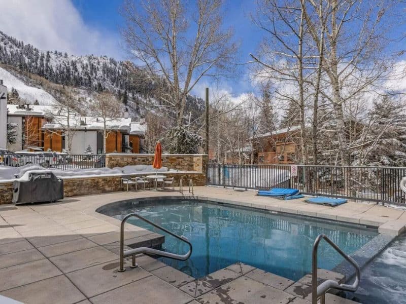 A swimming pool in Aspen with snowy mountains in the background.