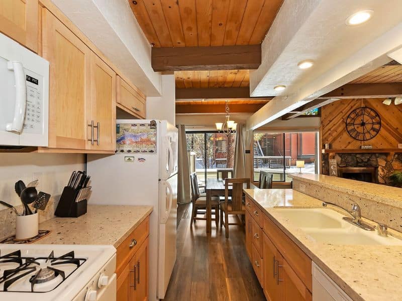 Bright kitchen space in a Big Bear cabin, complete with wooden cabinetry, modern appliances, and a breakfast bar overlooking the dining area.