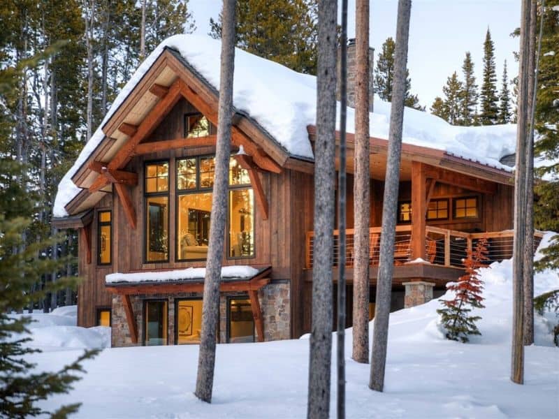 A Big Sky MT ski in ski out cabin rental nestled in the woods, surrounded by trees.