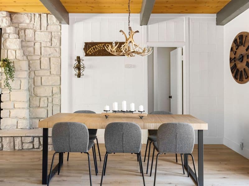 Elegant dining area with a stone column, antler chandelier, and a rustic table set in a cabin near Snow Summit in Big Bear.