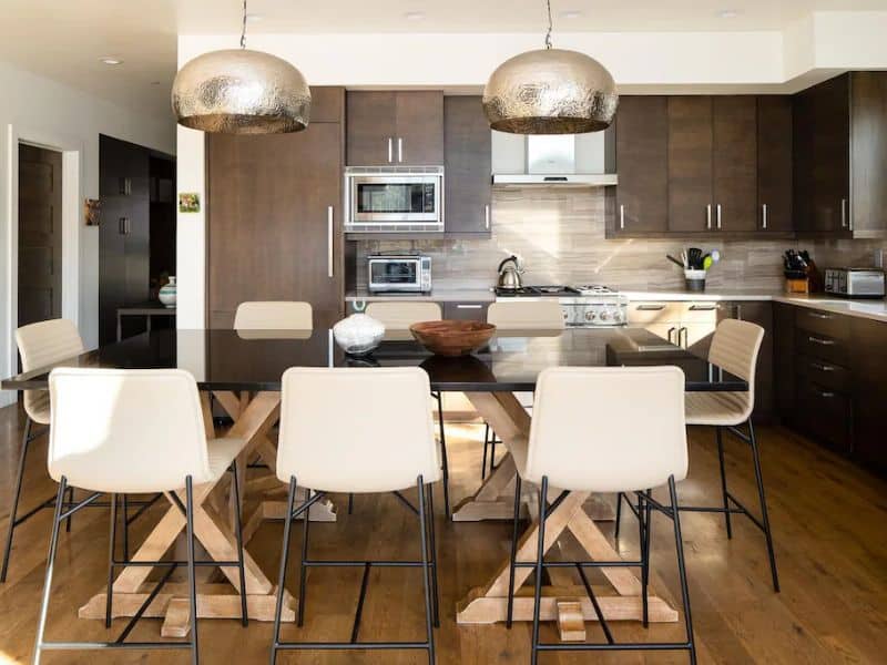 Contemporary kitchen with sleek design and a spacious dining area in a Big Sky vacation rental, featuring modern appliances and stylish lighting, ideal for family meals.