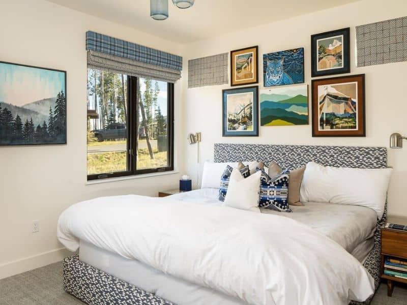 Bright and airy bedroom with a comfortable bed, adorned with local art and large windows in a Big Sky Montana holiday rental.