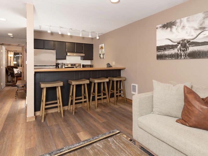 A Big Sky Montana ski in ski out rental with a living room, kitchen, and bar stools.