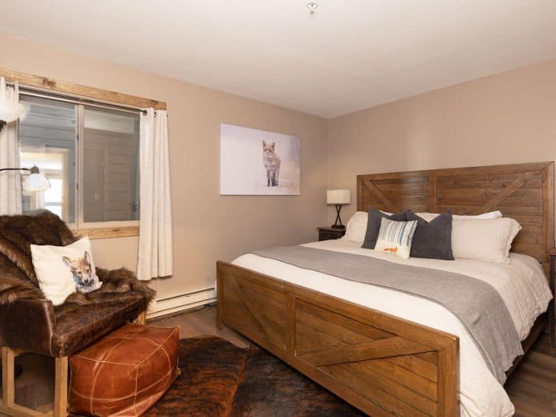A Big Sky MT rental with a bedroom with a bed, chair, and foot rest.