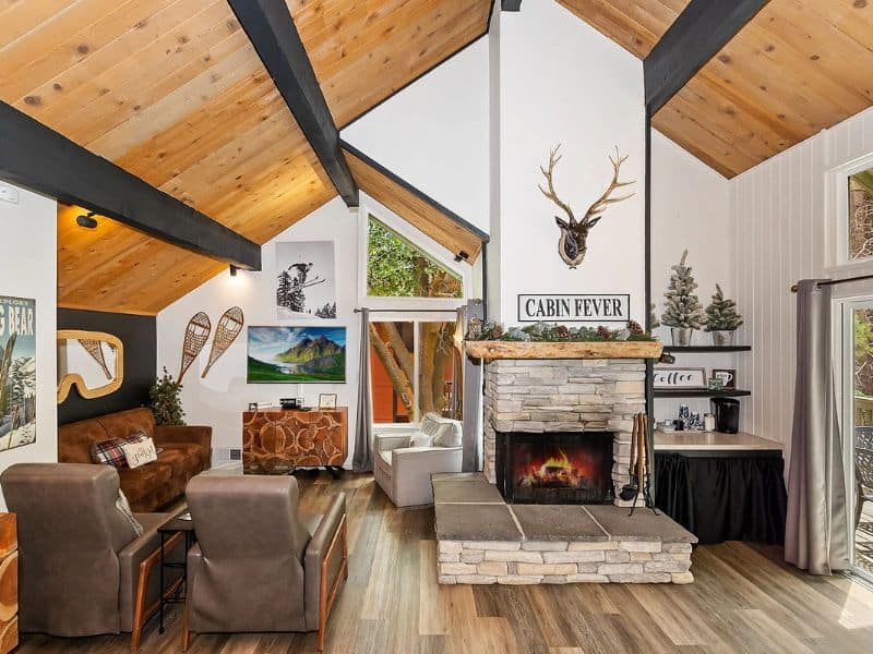 Spacious living area in a Big Bear winter cabin rental with vaulted ceilings, a stone fireplace, and mountain decor.
