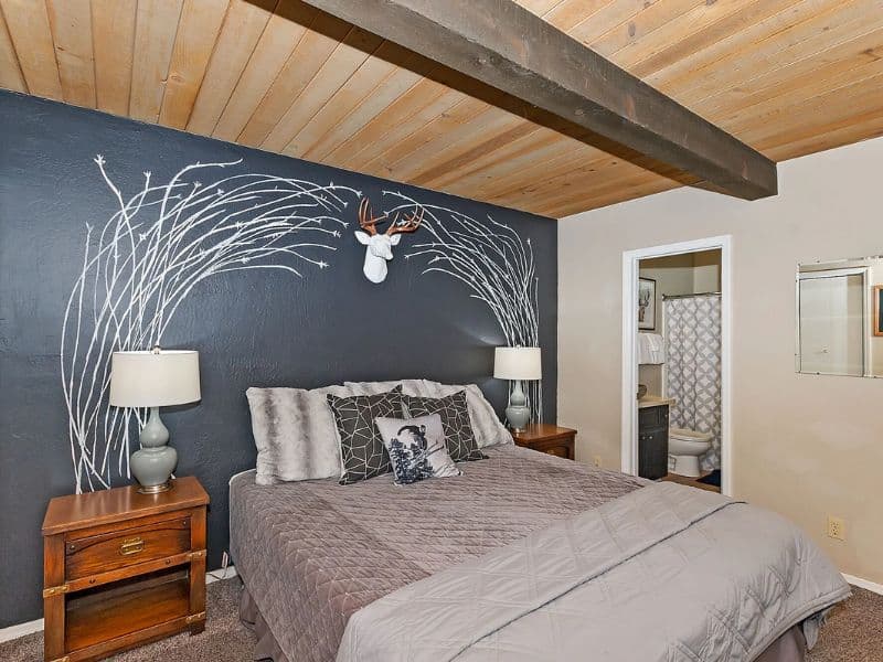 Bedroom with a dark accent wall featuring white birch tree art, offering a stylish retreat in a Big Bear cabin rental.